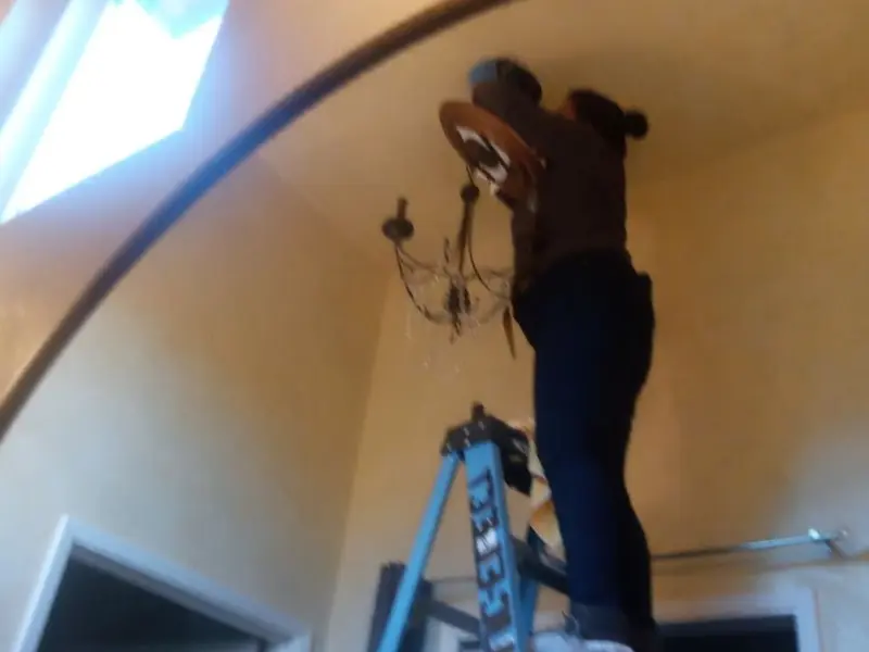 Electrician installing a chandelier in a Pocopson residence
